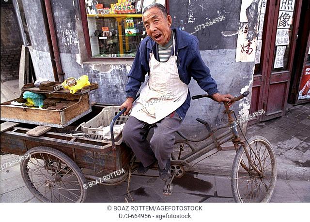 A man rests in a narrow street in the old city of Ping Yao. Shanxi, China
