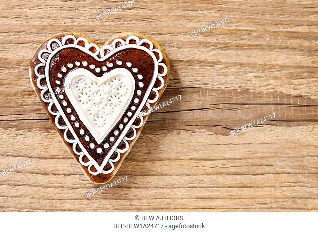 Gingerbread cookie in heart shape on a wooden background, copy space