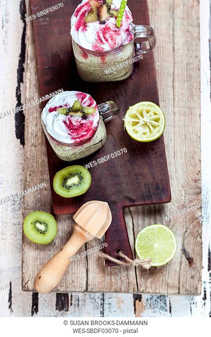 Two glasses of kiwi limes smoothie with coconut cream and raspberry sauce