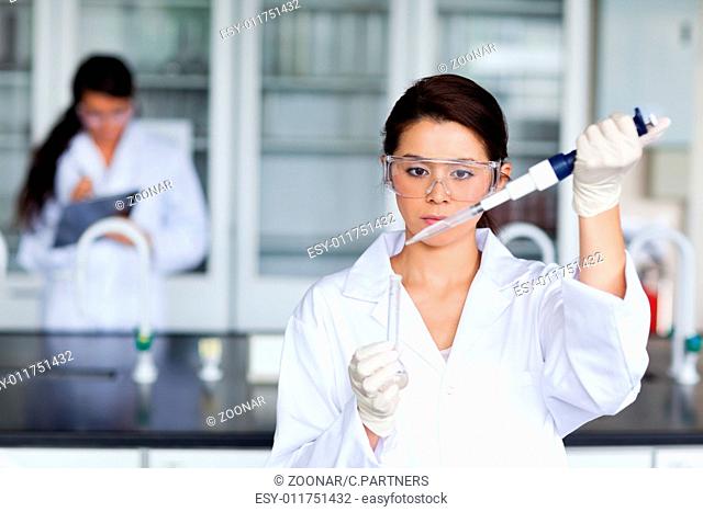 Female scientist pouring a liquid in a tube