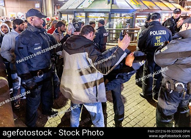 16 December 2023, Hamburg: Police officers search people for weapons and other prohibited items at a checkpoint at Hamburg Central Station