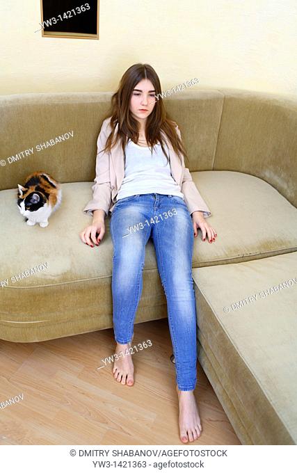 Portrait of a young blond woman in jeans lying on sofa