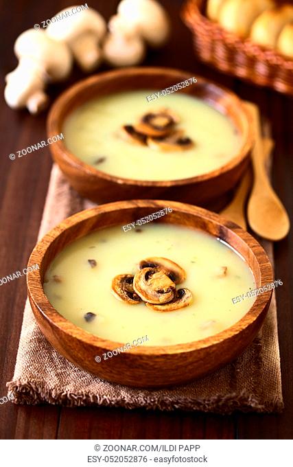 Mushroom cream soup garnished with roasted mushroom slices served in wooden bowls, photographed with natural light (Selective Focus