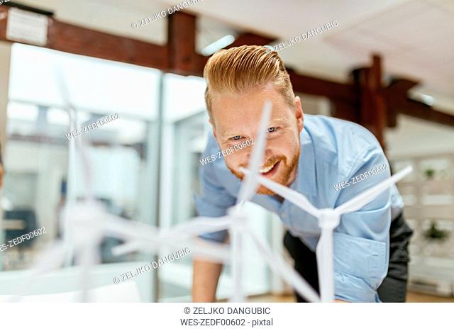 Businessman in office looking at models of wind turbines