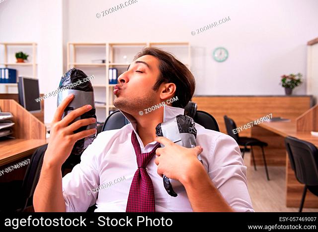 Young drug addicted male employee sitting at workplace