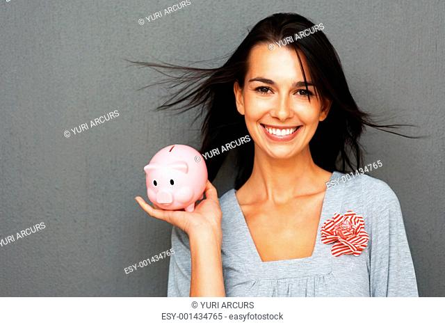 Smiling woman holding piggy bank in one hand