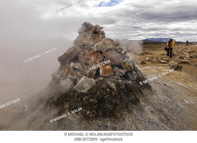 Photographer with mud pots, steam vents, and sulphur deposits at HveraroÌ. nd, north coast of Iceland