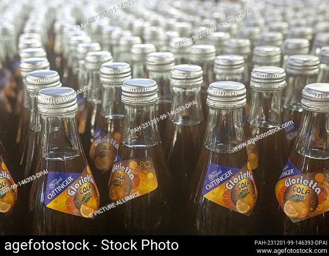 01 December 2023, Bavaria, Oettingen: A cola mix drink is filled into crates at the Oettinger brewery. Due to the difficult situation on the German beer market