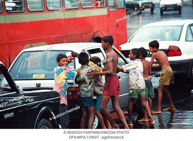 Street children cleaning car glass in monsoon ; Bombay Mumbai ; Maharashtra ; India