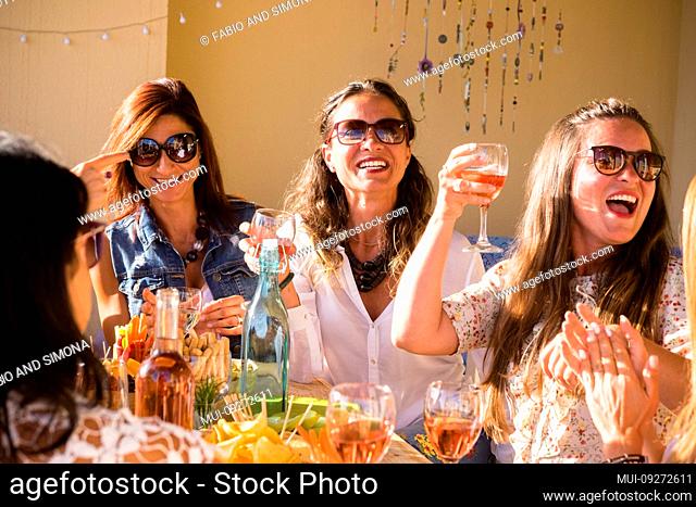 Group of caucasian people women friends celebrate together with table full of food and toasting with red wine - happiness and friendship for adult and young...
