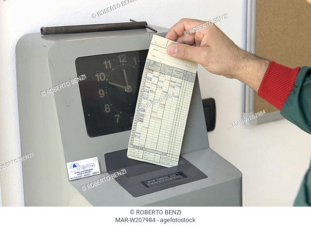 worker place timecards in clocking in machine