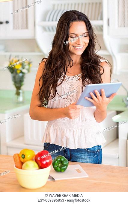 Pretty brunette using tablet pc and preparing salad
