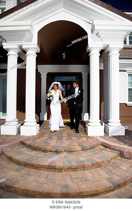 Newlywed couple walking down the steps in front of a building