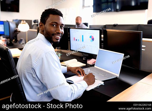 Happy african american man working on laptop in office