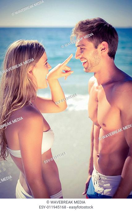 Pretty blonde putting sun tan lotion on her boyfriend
