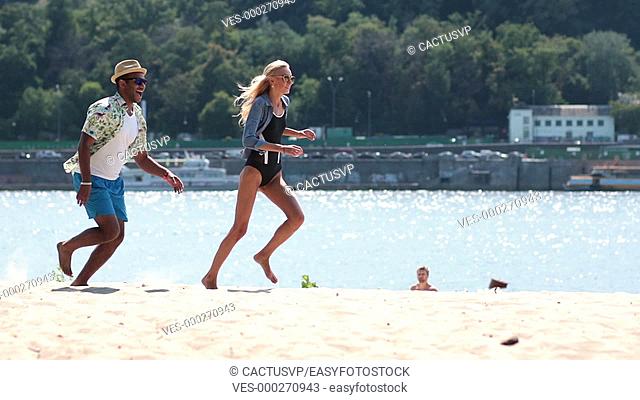 Happy couple playing and running on beach shore