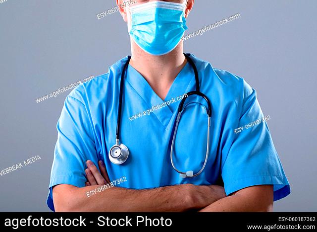 Caucasian male doctor wearing face mask, isolated on grey background
