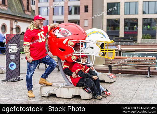 05 November 2023, Hesse, Frankfurt/Main: Father Oliver (l-r) and his two sons Jan and Noah have their photo taken with an oversized Kansas City Chiefs helmet in...
