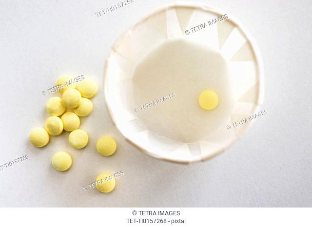 Yellow pills with cup, studio shot