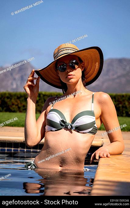 Portrait of woman with hat and sunglasses in the pool