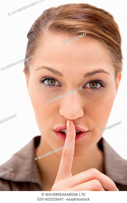 Young woman asking for silence against a white background