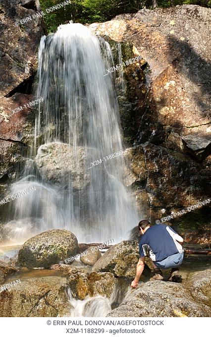 A hiker explores Thirteen Falls along Franconia Brook in the Pemigewasset Wilderness in Franconia, New Hampshire USA