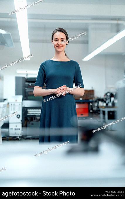 Female professional with hands clasped standing in workshop