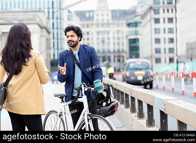 Business people with bicycle talking on urban bridge