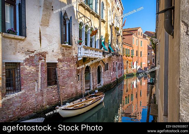 Boats on small canal among old old houses in Venice, Italy