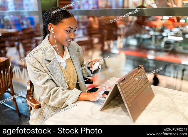 Girl making online payment through credit card on touch screen laptop at cafe