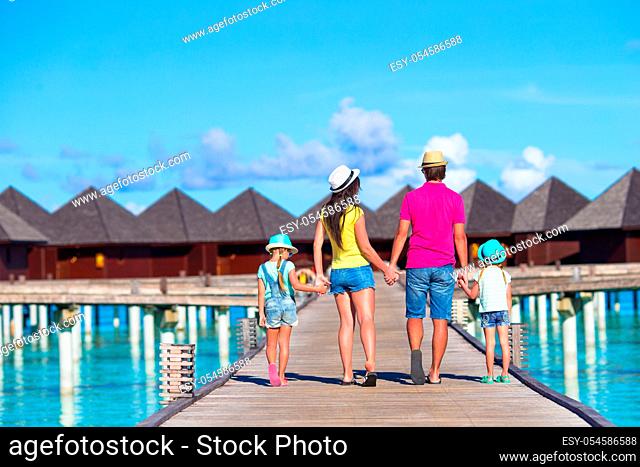 Back view of beautiful family of four on beach during summer vacation