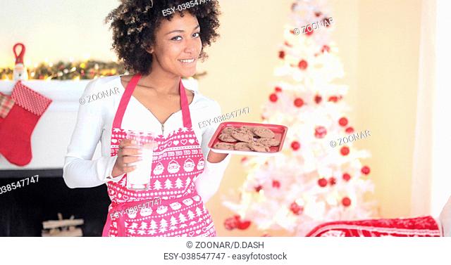 Cute young woman holding milk and cookies