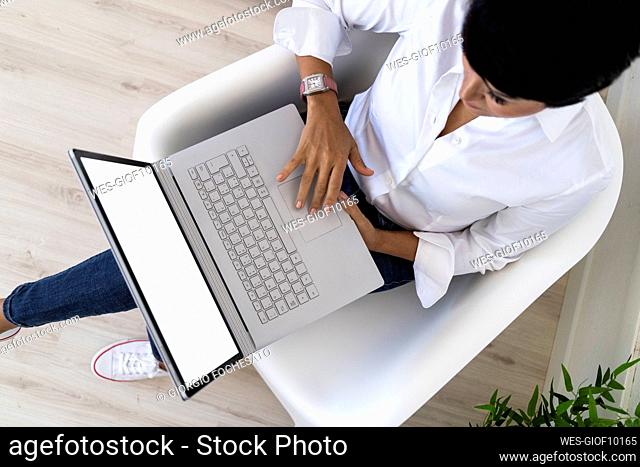 Businesswoman sitting in office armchair with laptop