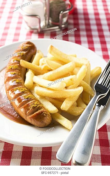 Currywurst sausage with ketchup & curry powder & chips in restaurant