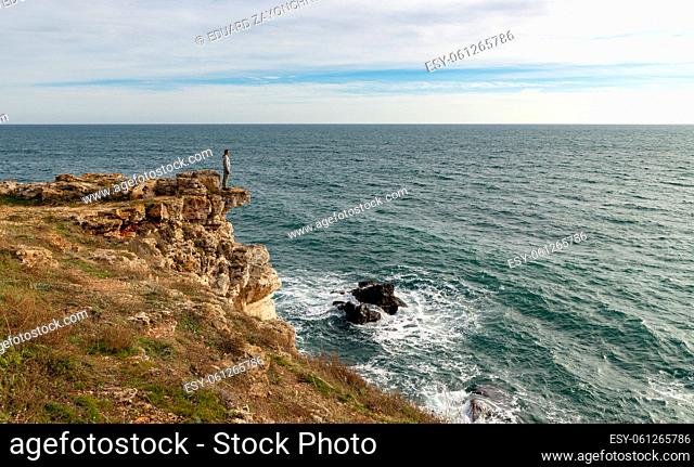 A man enjoys a beautiful sea view from the top of a cliff