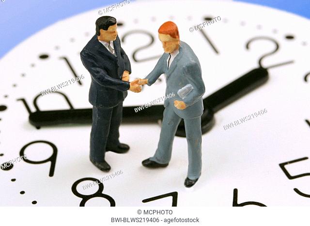 little figures on a clock shaking hands