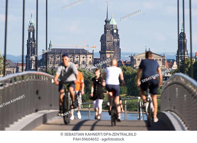 Cyclists and pedestrians cross the Molen Bridge with the Dresden Cathedral (L-R), Castle tower, City Hall tower, Semper Opera