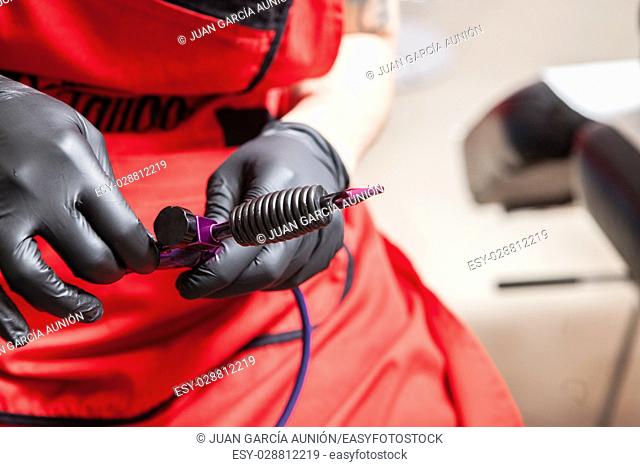 Tattoo artist adjusts the gun ink machine. Closeup