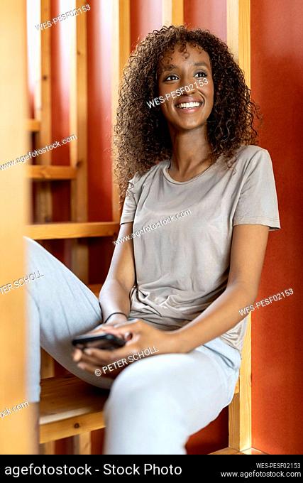 Woman looking away while sitting on staircase at home