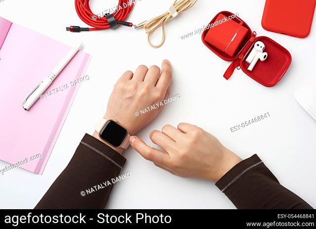 smart watch with a blank black screen is on his left hand, his right hand is touching the watch screen, freelancerâ. . s workplace with an open notebook