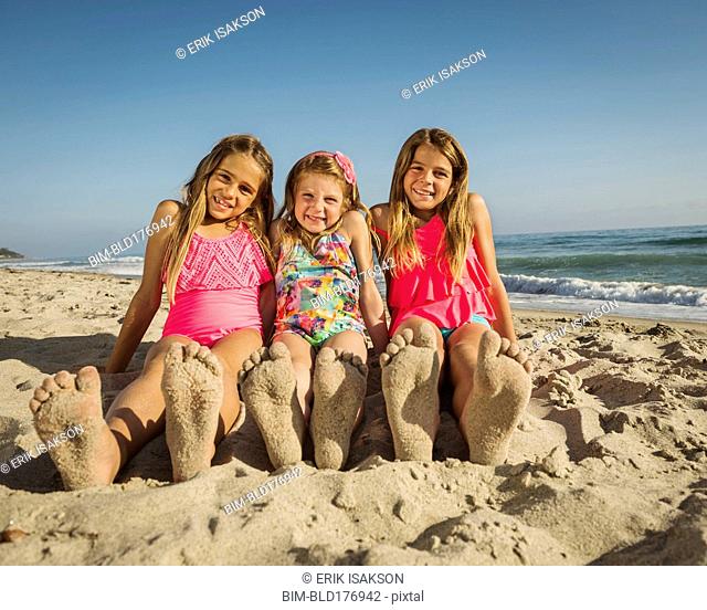 Caucasian sisters with sandy feet on beach