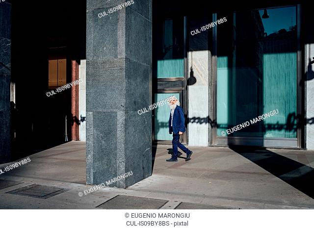Senior businessman passing office building, Milano, Lombardia, Italy