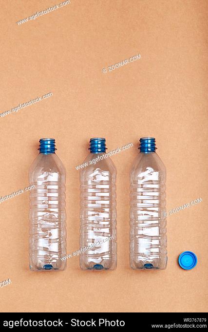 Empty plastic bottles put in a row, over cardboard background. Collecting plastic waste to recycling. Concept of plastic pollution and too many plastic waste