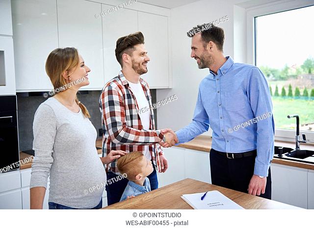 Family and real estate agent shaking hands in kitchen of new apartment
