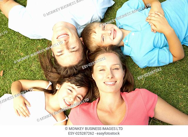 Overhead View Of Young Family Lying On Grass In Park