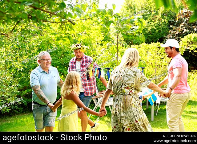 Family dancing in garden around maypole
