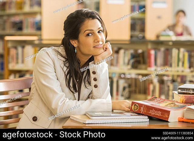 Mixed Race woman with books in library