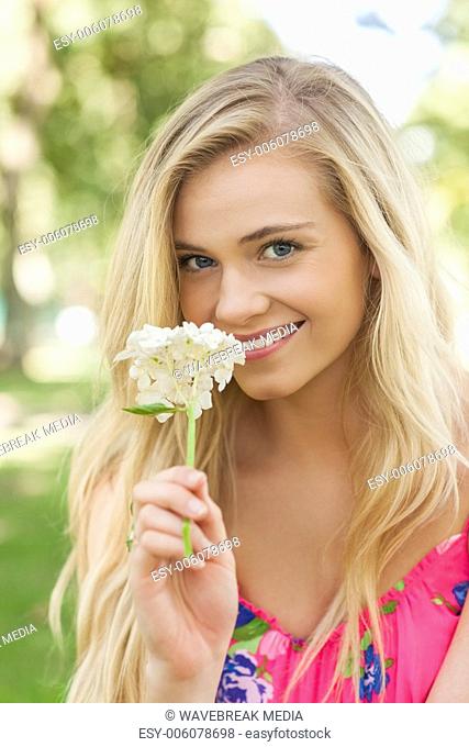 Pretty young woman smelling a white flower