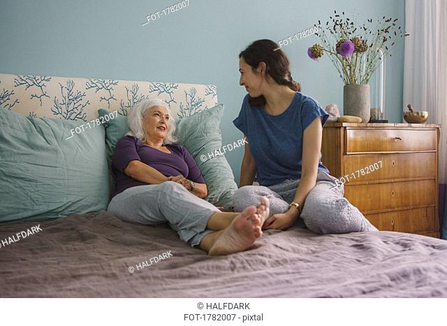 Senior mother talking with daughter on bed