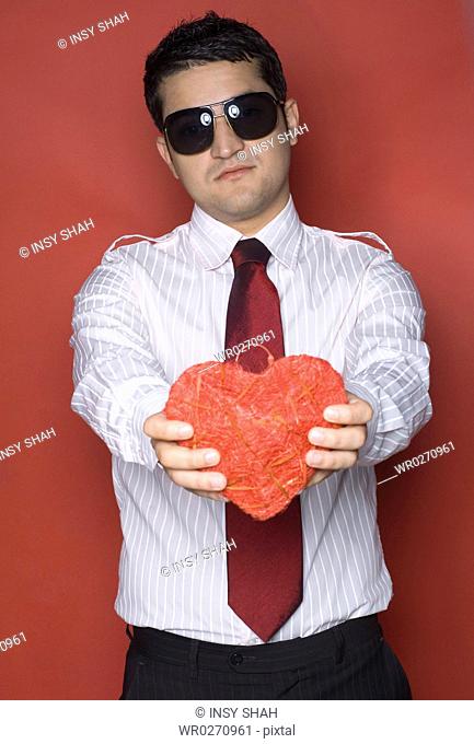 Portrait of a young man holding a heart shaped object